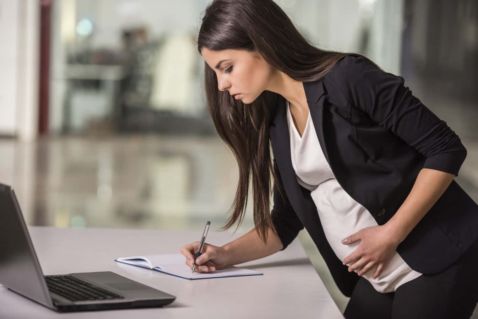 Pregnant business woman working in office.